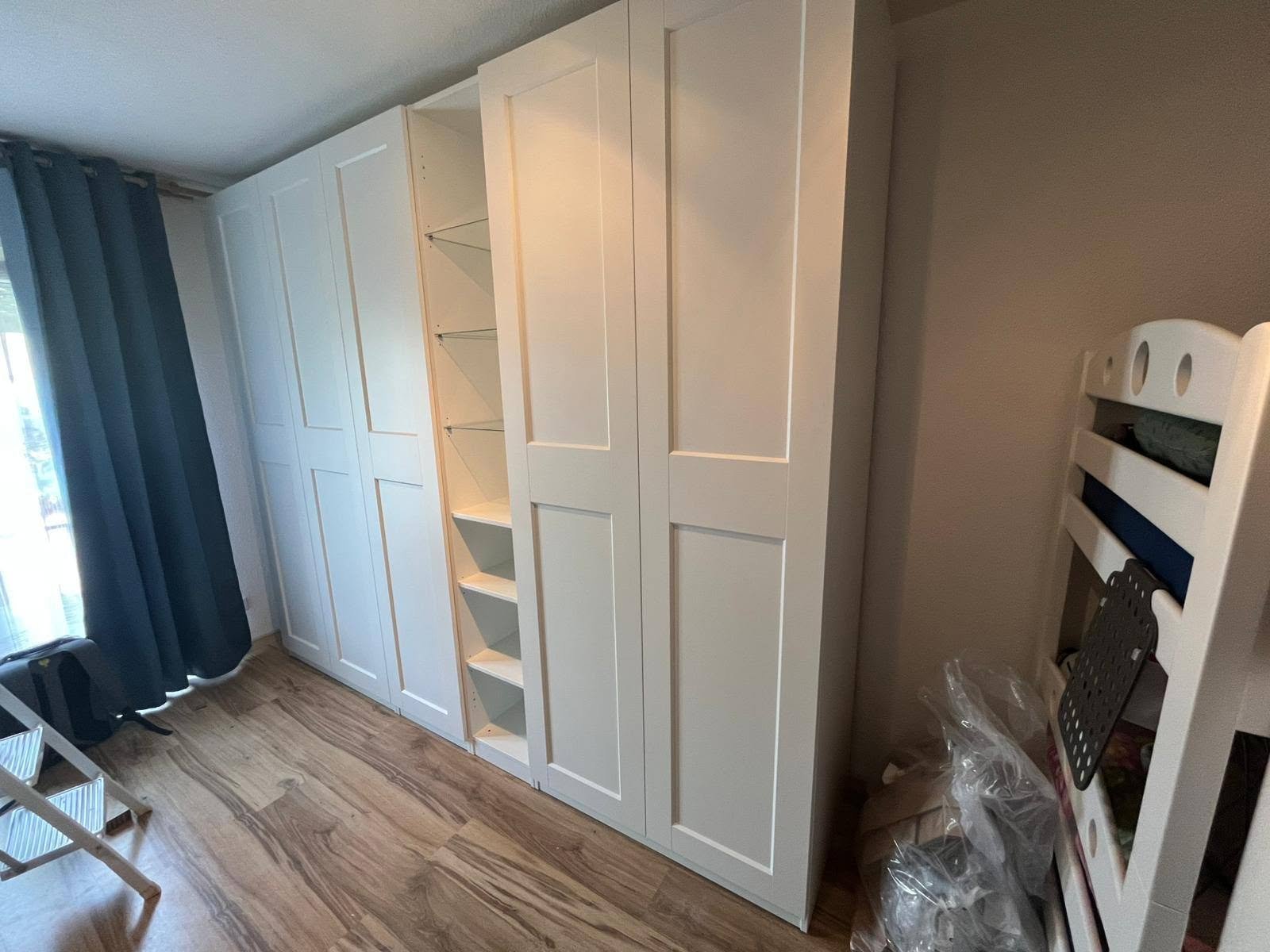 White wardrobe storage system with panel doors and open central shelves from our assembly work
