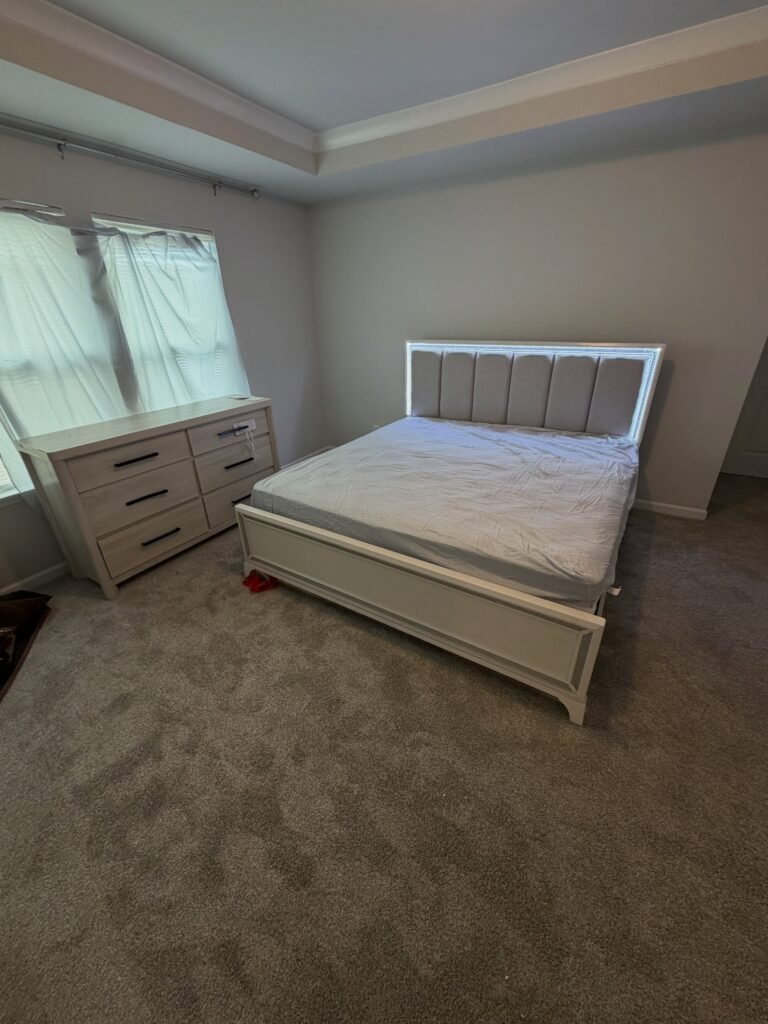 Light-colored bed with an upholstered headboard beside a separate six-drawer dresser from our furniture assembly portfolio