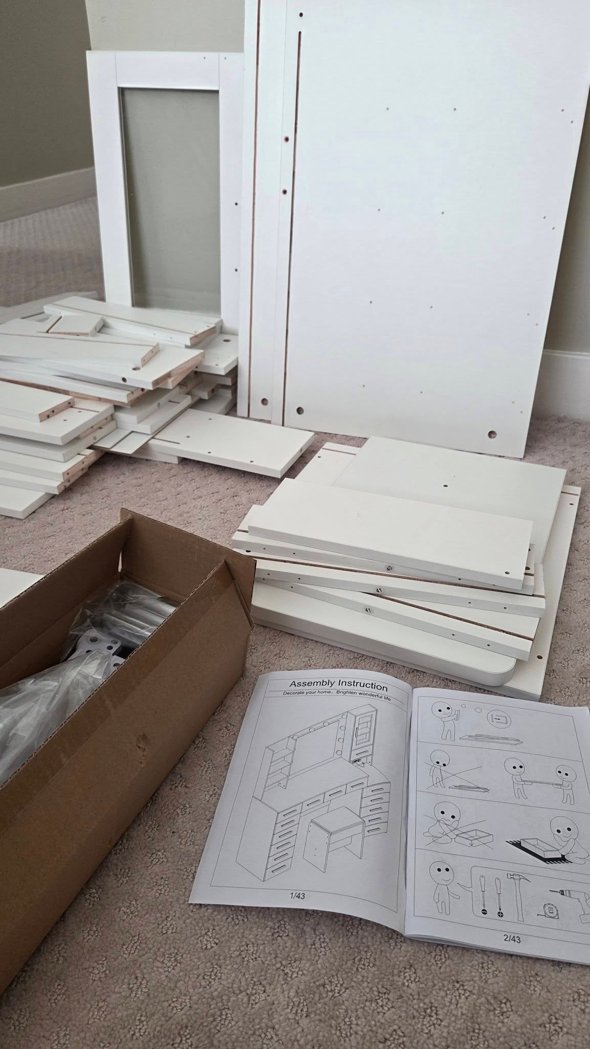 White vanity panels, fittings and the supplied instruction booklet laid out before assembly