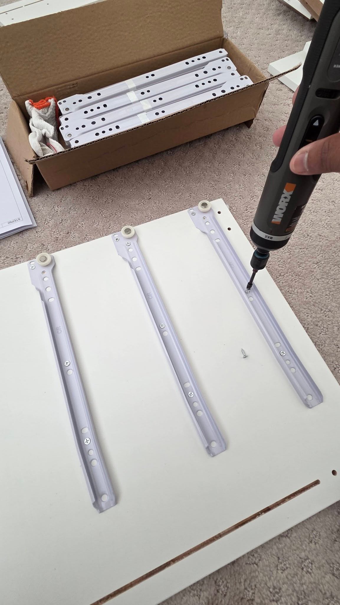 Roller drawer runners being fastened to a white vanity panel during assembly