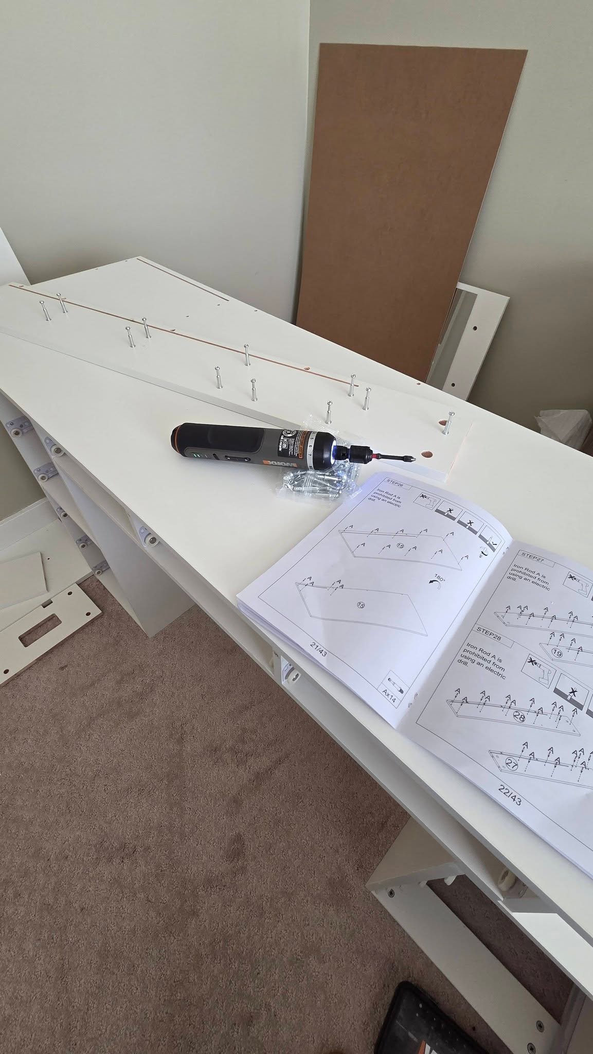 Partly assembled white vanity frame with connecting hardware and an open instruction booklet
