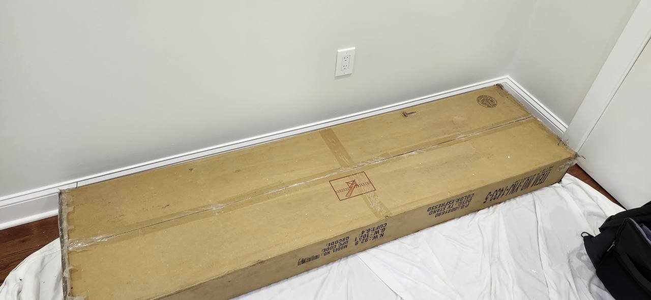 Long cardboard TV console carton resting beside the assembly area