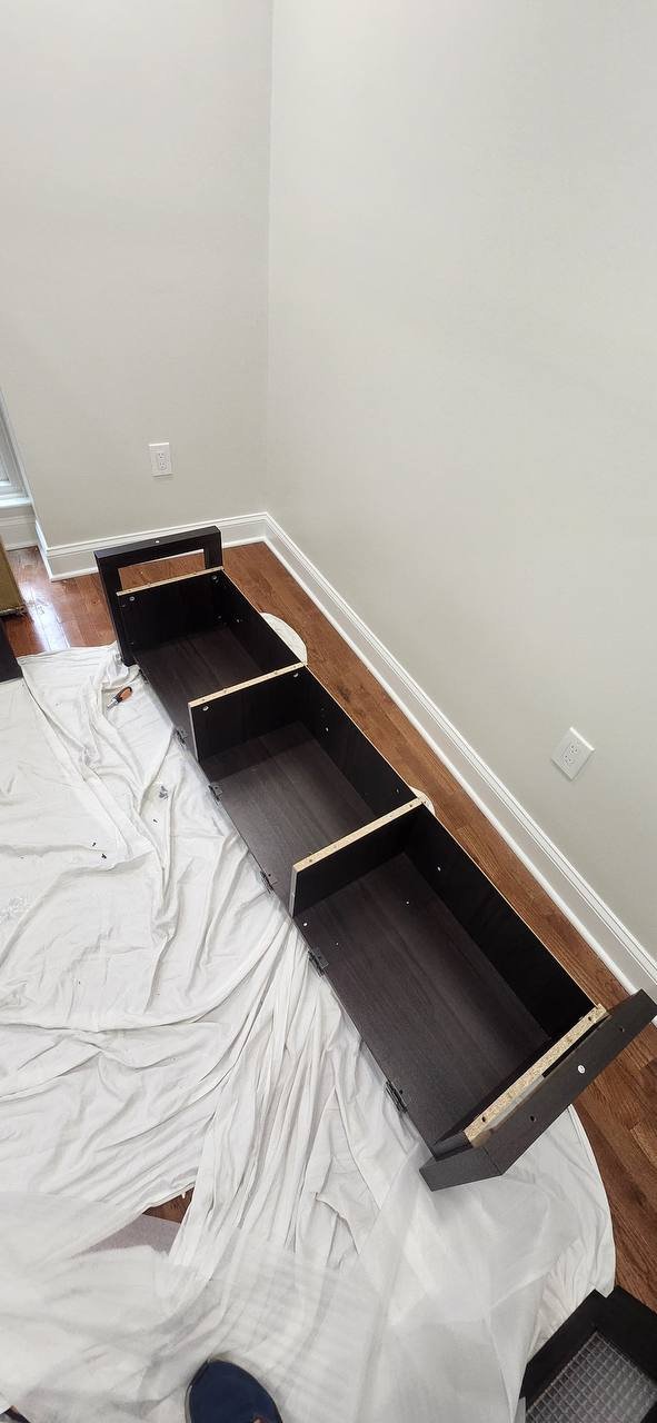 Partially assembled TV console frame with interior dividers on a protective sheet